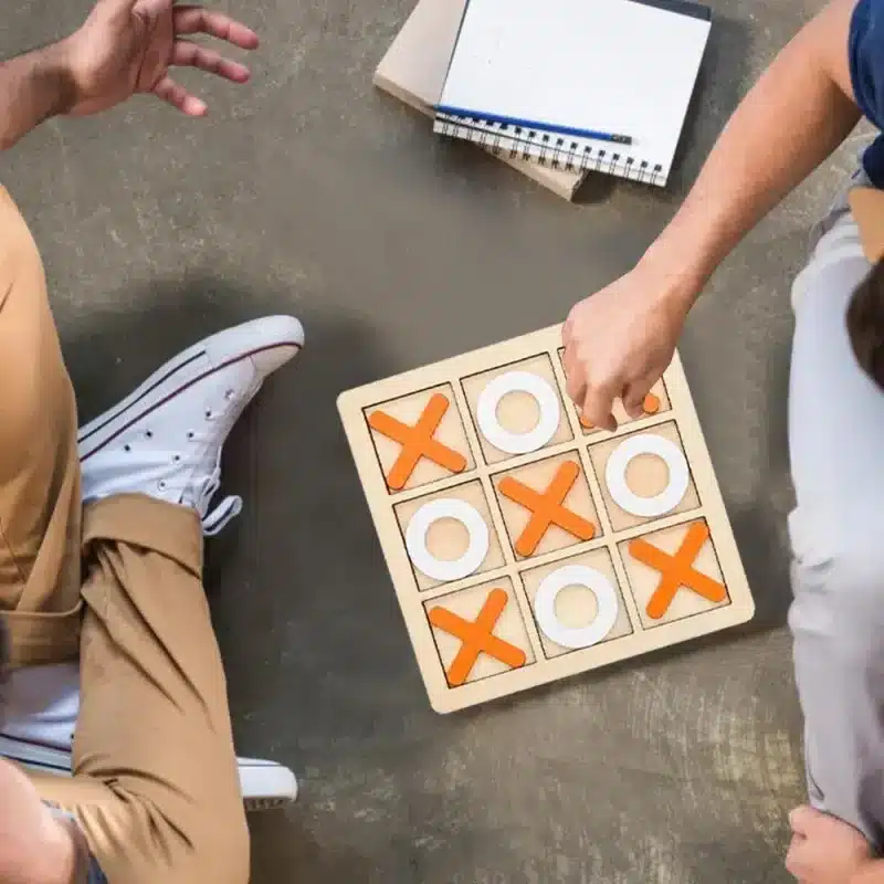 Two men playing wooden Tic Tac Toe.