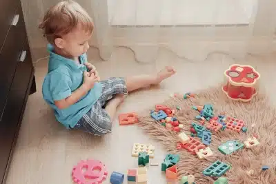 Enfant de 2 ans dans sa chambre devant des jeux Montessori 