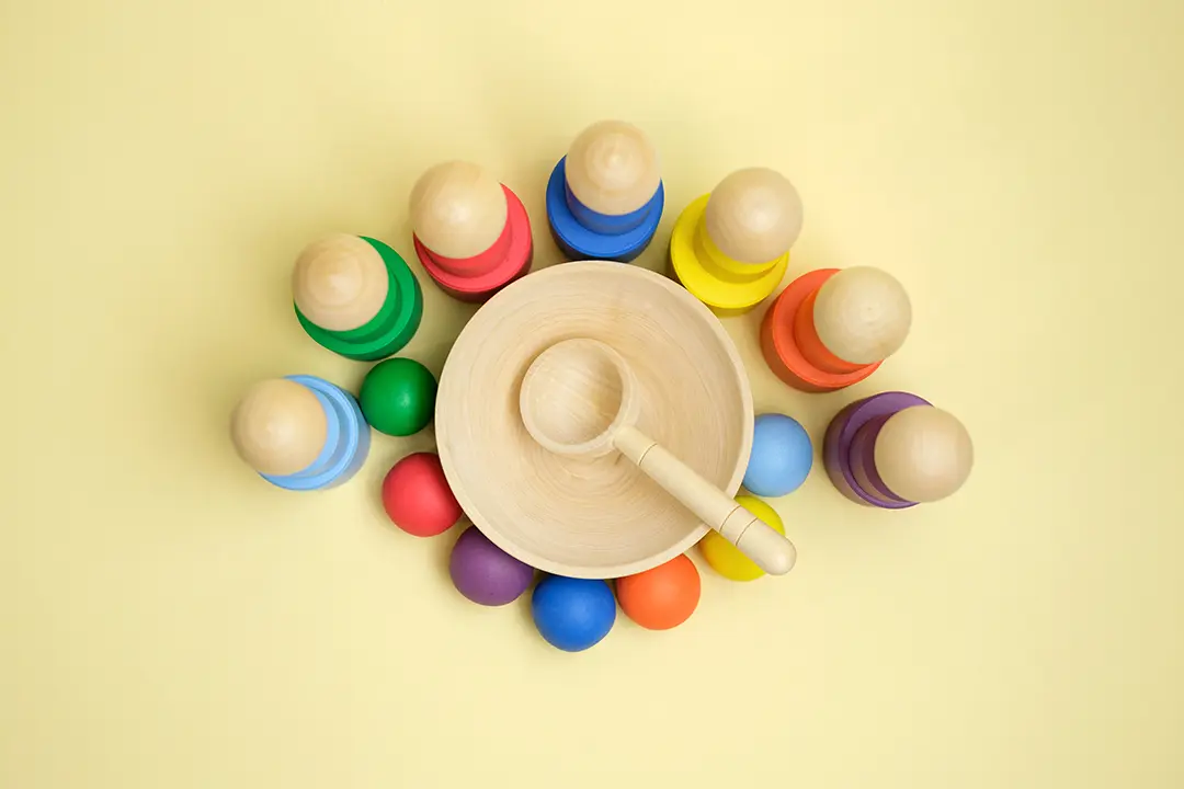 Colorful wooden toys designed for the development of a child's philosophy and Montessori education, presented on a yellow background.