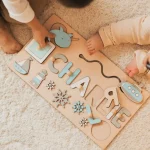 Two children playing on a Personalized First Name Puzzle board - made of wood with the first name Charlie.