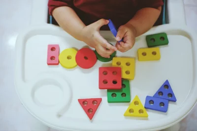 Vue depuis dessus des mains d'un enfant de 3 ans jouant a un jeux coloré de pièces