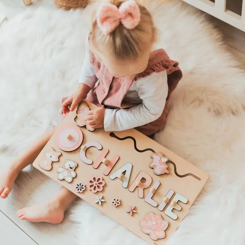 Ein kleines Mädchen spielt mit einem personalisierten Puzzle mit Vornamen - aus Holz.