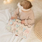 Une bébé fille joue avec un puzzle personnalisé prénom en bois - cadeau unique et éducatif qui dit Evelyn.