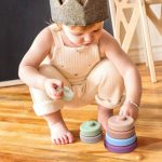 Un bébé joue avec un ensemble de 6 blocs de construction en silicone souple pour bébé sur le sol.