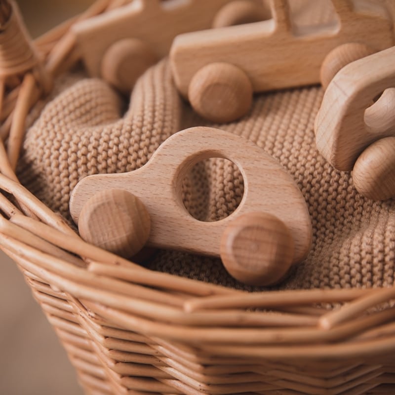 A basket filled with little wooden cars and a wooden teething ring - Cars.