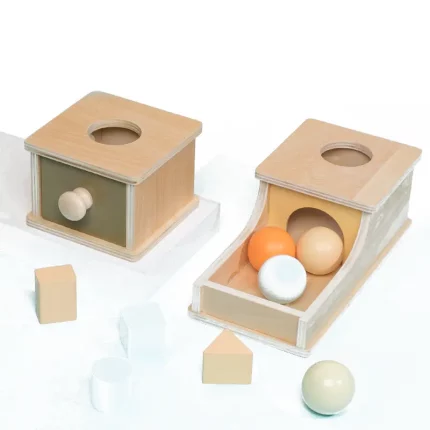 A Montessori Object Permanence Box - Balls with a wooden cube inside.