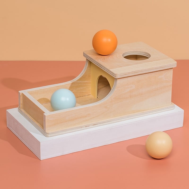 Eine Montessori-Gegenstands-Standortkiste - Holzbälle mit Bällen darauf.