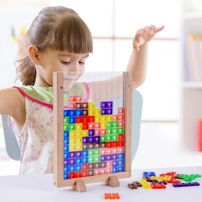 Une petite fille joue avec un jeu de Tetris en bois.