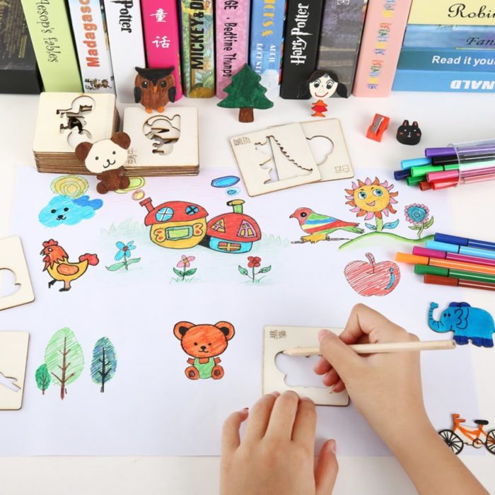 Un enfant utilise Pochoirs en Bois Montessori pour Enfants - 20 pièces pour dessiner sur une feuille de papier.