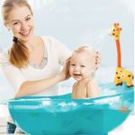 Ein Baby wird mit einem Spielzeug-Wasserstrahlregner - Giraffe gebadet.