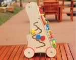 A colorful wooden Baby Walking Cart on a wooden table.