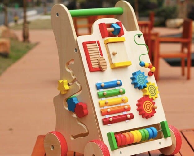 A Baby Walking Cart - Vibrantly colored on a wooden table.