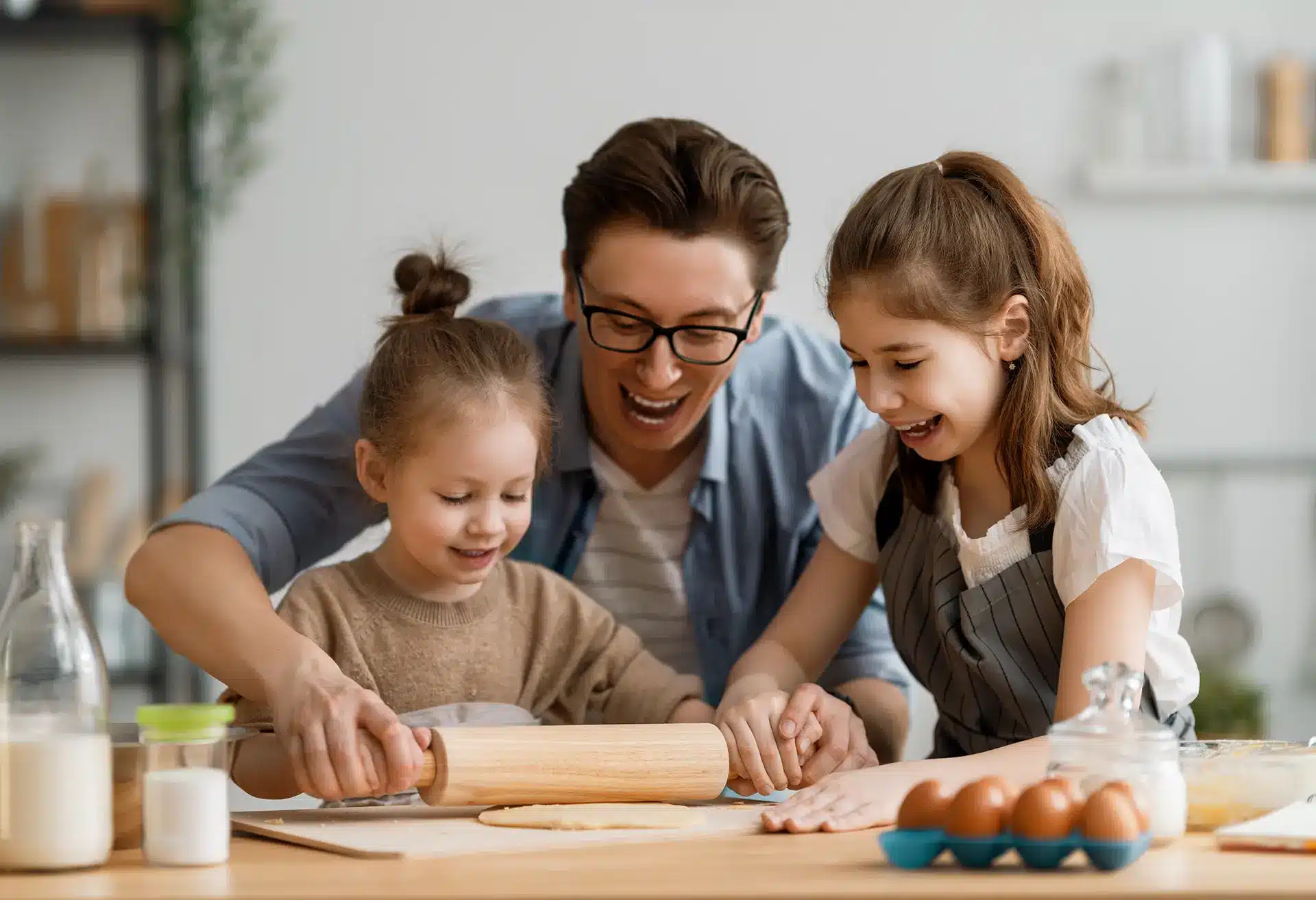 Ein Mann und seine beiden Töchter beschäftigen sich in der Küche mit Montessori-inspirierten Aktivitäten.