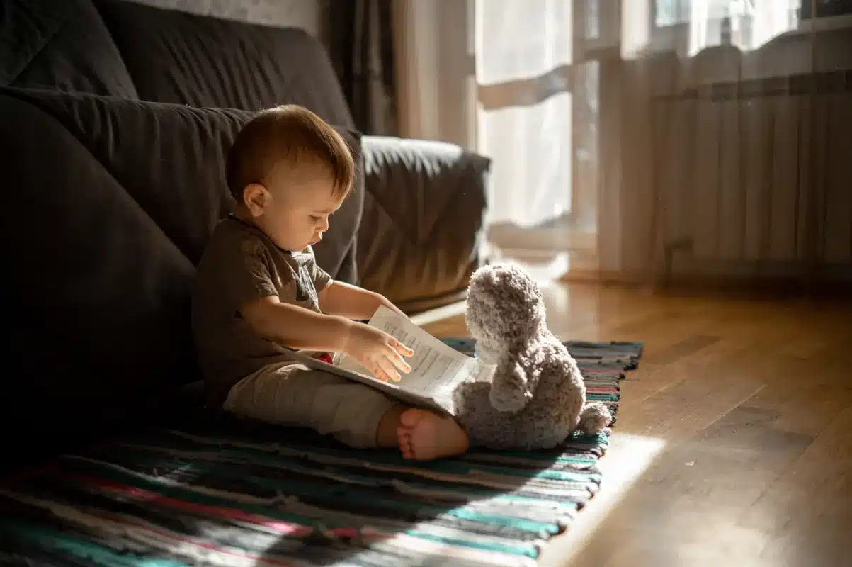 A baby reading a book, exploring the pages while wiggling.