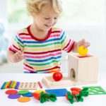 Ein kleines Kind, das mit einer Reihe von Holzspielzeugen spielt Permanentbox 4 in 1.