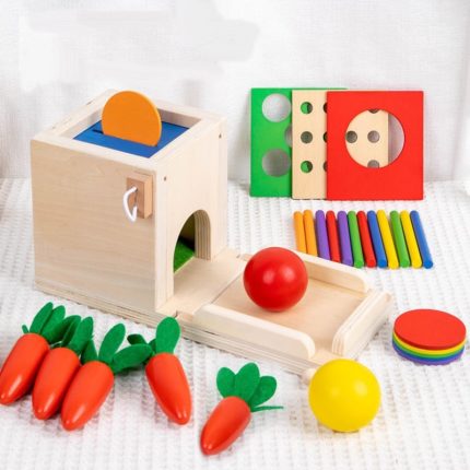 Un ensemble de jouets en bois avec des carottes et d'autres jouets emballés de manière pratique sous forme de Boite de permanence 4 en 1.