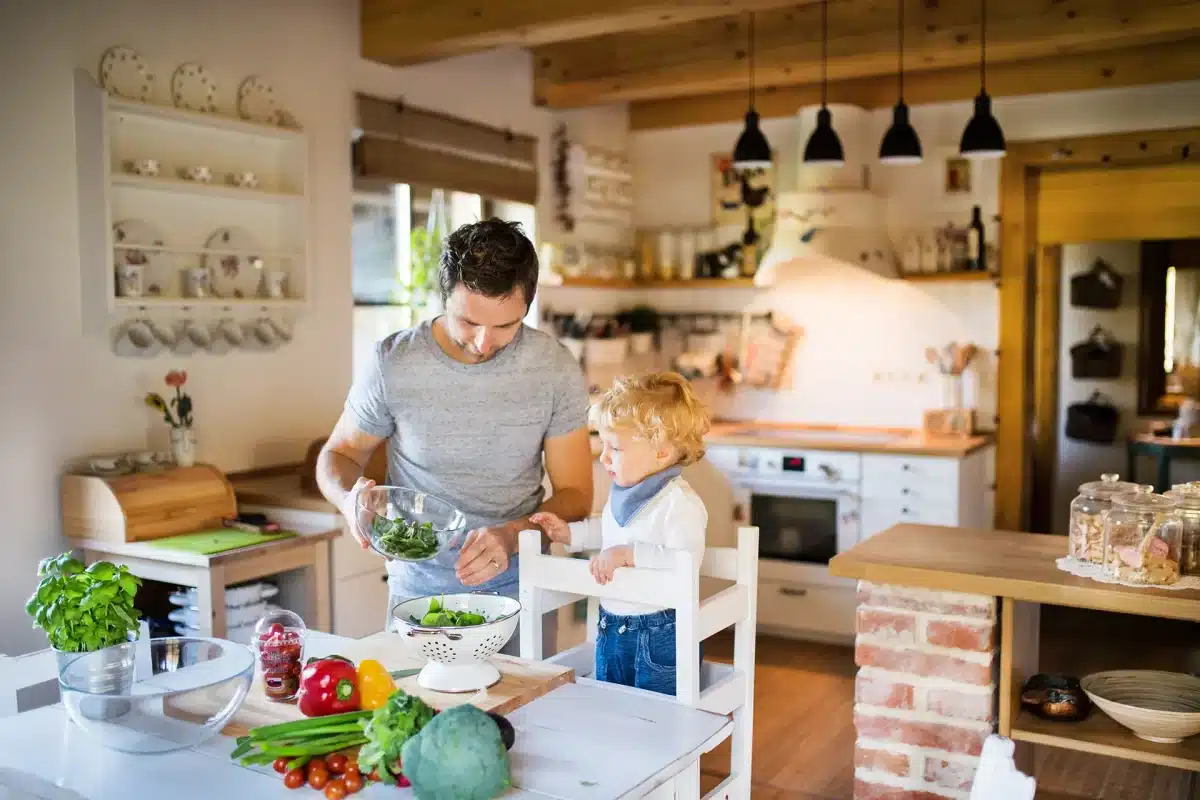 Un homme et un enfant vivant une expérience éducative dans une cuisine Montessori.