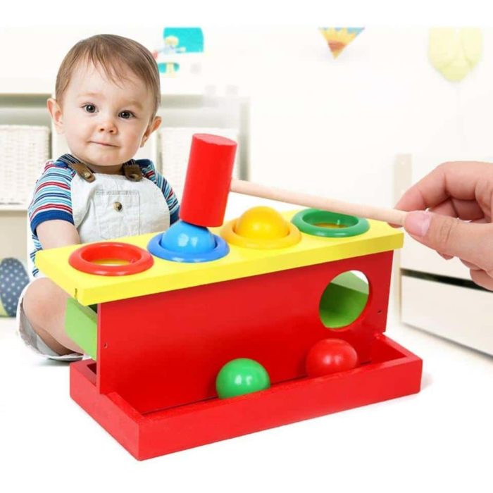 Ein Baby spielt mit einem 4-Farben-Holzklopfspiel.