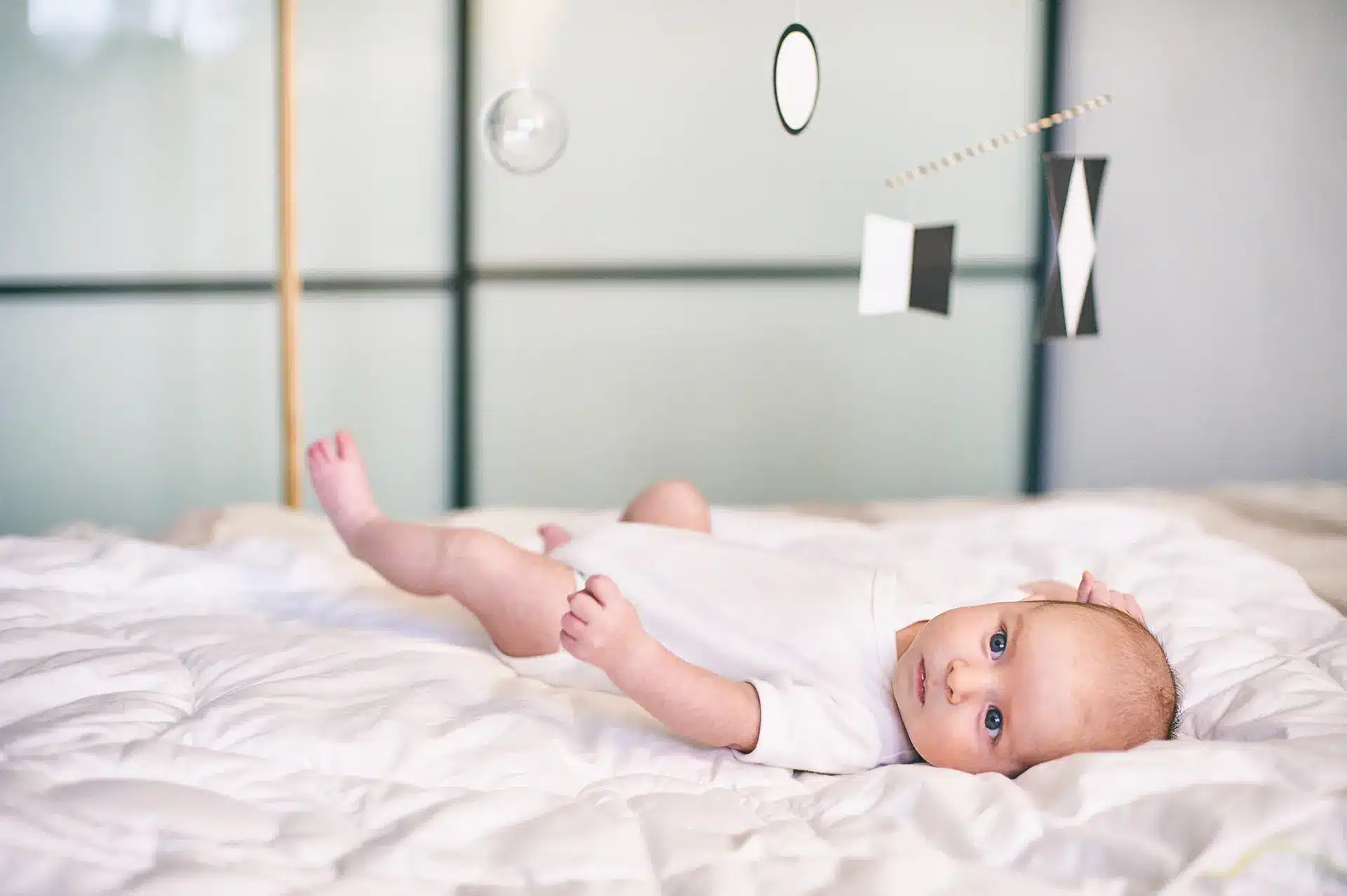 A Montessori baby resting on a white bed.