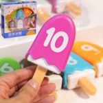 A person holding a Children's Math Toy - Ice Cream with a number on it.