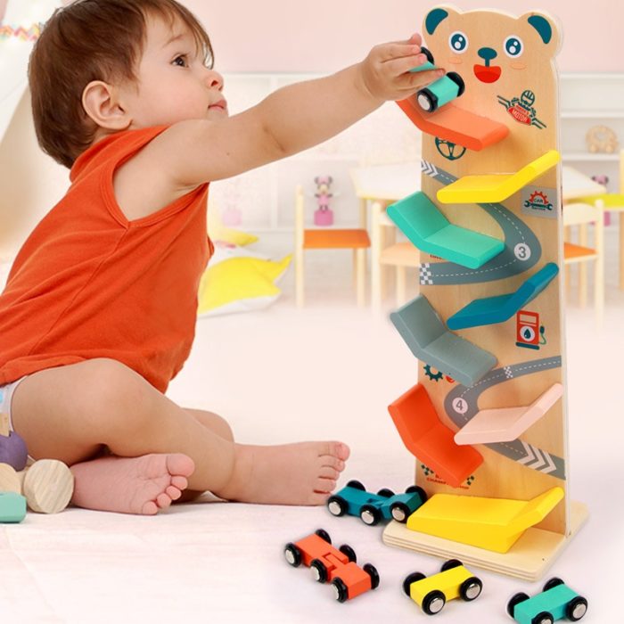 A toddler plays with a Votures Wooden Ramp - Racetrack for Toddlers, using the ramp to race little cars.