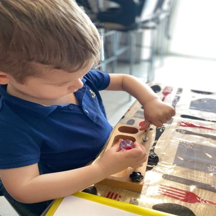 A young boy playing with the Vrai Outils pour Enfants à Visser at a table.