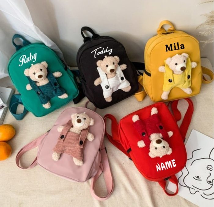 A group of teddy bear backpacks with names on them.