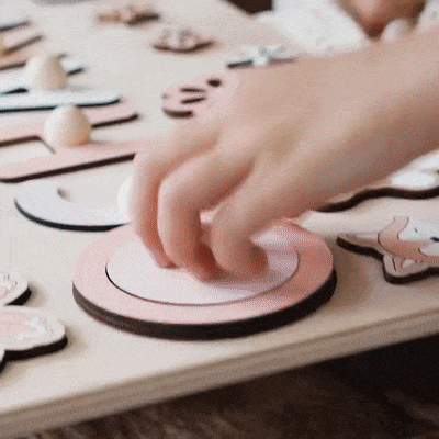 Un enfant joue avec une planche de bois sur laquelle sont inscrites des lettres.