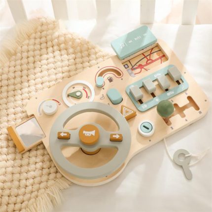 A wooden toy steering wheel on a bed.