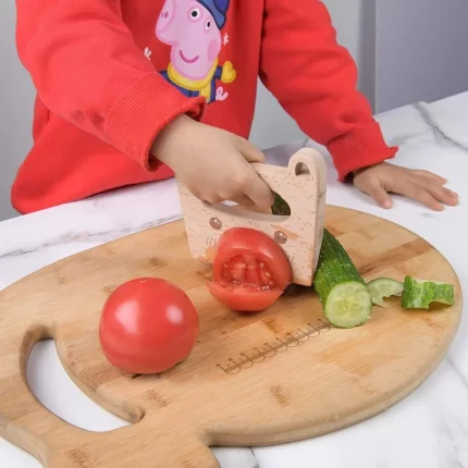 A child cuts vegetables on a wooden chopping board.