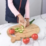 Un enfant coupe des légumes sur une planche à découper en bois.