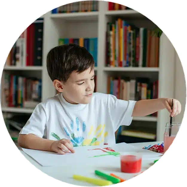 Ein Junge sitzt in seinem neuen Zuhause an einem Tisch mit Farben und Stiften.