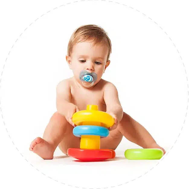 Ein Baby spielt in seinem neuen Zuhause mit bunten Spielsachen auf weißem Hintergrund.