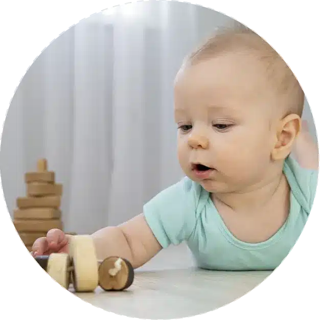 A new baby plays with wooden blocks at home.