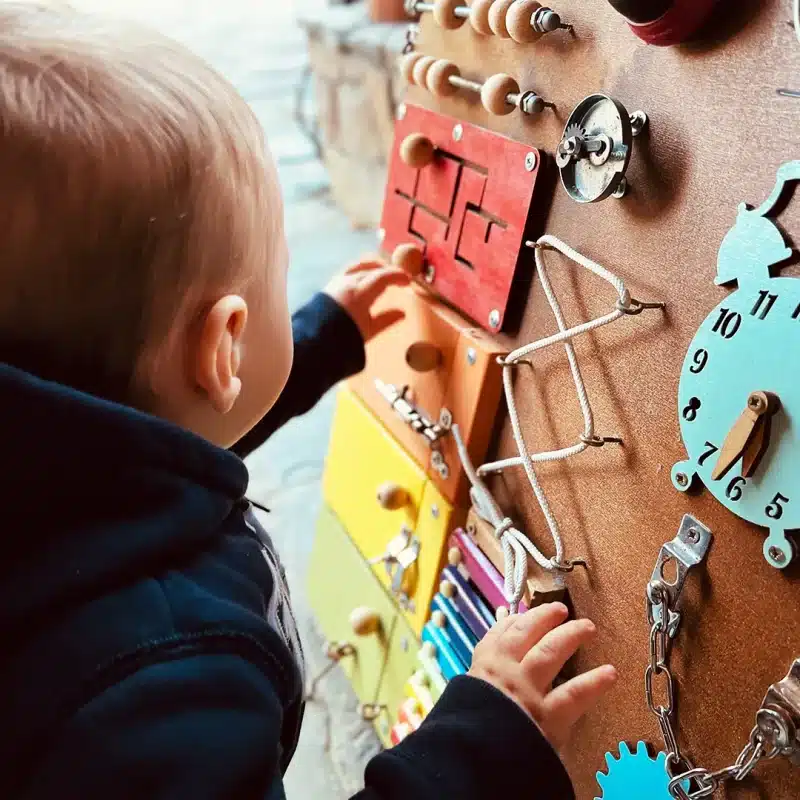 Ein Kind spielt mit einem Holzbrett voller Spielsachen.