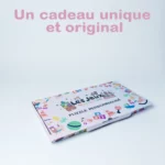 Une boîte à puzzle personnalisée avec des éléments de design colorés, avec « Puzzle Personnalisé Prénom en Bois », se dresse sur un fond blanc. Le texte rose au-dessus dit : « Un cadeau unique et original.