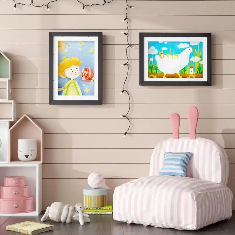 Un coin chambre d'enfant cosy avec des décorations murales fantaisistes, un fauteuil rose rayé avec des oreilles de lapin, des peluches et un Cadre pour dessins d'enfants pour stocker des dessins - taille A4.