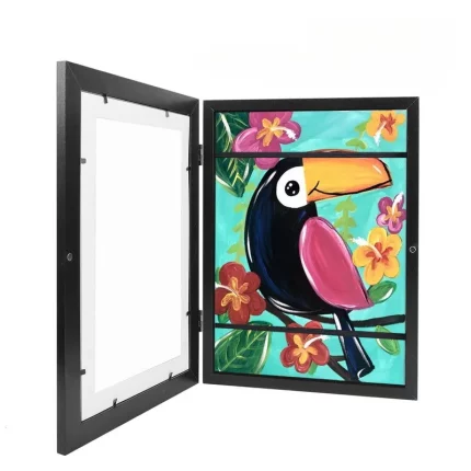 Peinture colorée représentant un toucan entouré de fleurs, présentée dans un cadre noir ouvert.