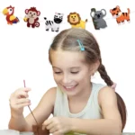 Une fille avec des nattes sourit pendant qu'elle peint, inspirée par les animaux colorés de la jungle sur le mur, parfait pour créer avec le Kit de Couture Enfants - Porte-clés à Faire Soi-Même Sans se piquer le doigt.