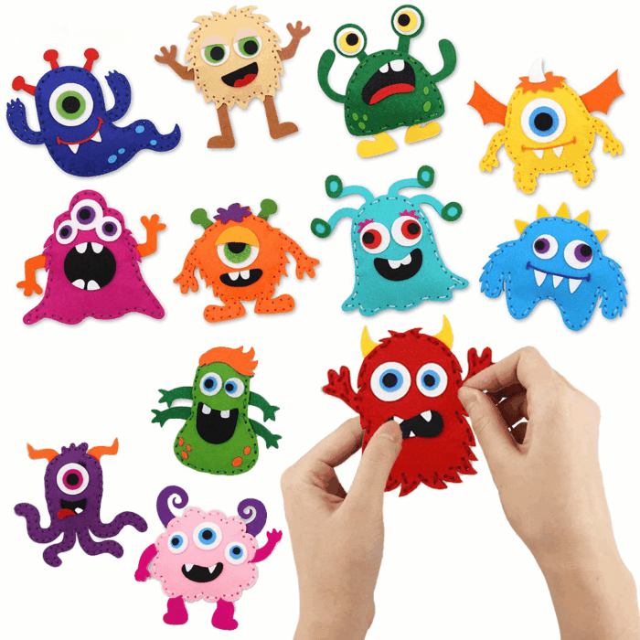 Une paire de mains assemble un porte-clés monstre en feutre rouge du Kit de Couture Enfants - Porte-clés à Faire Soi-Même Sans se piquer le doigt, entouré d'autres objets artisanaux monstres en feutre colorés sur une surface blanche.