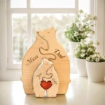 Le Puzzle Personnalisé De Famille D'ours En Bois est une charmante sculpture en bois étiquetée « Maman », « Papa », « Jess » et « Luke », avec une découpe en forme de cœur. Des fleurs blanches dans un pot ornent l'arrière-plan près de la fenêtre, ajoutant une touche sereine à cette charmante pièce.