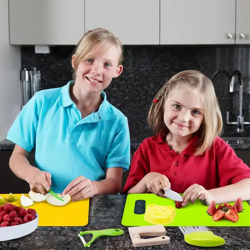 Deux enfants souriant tout en coupant des fruits sur des planches à découper colorées dans une cuisine, créant un moment parfait #118938.