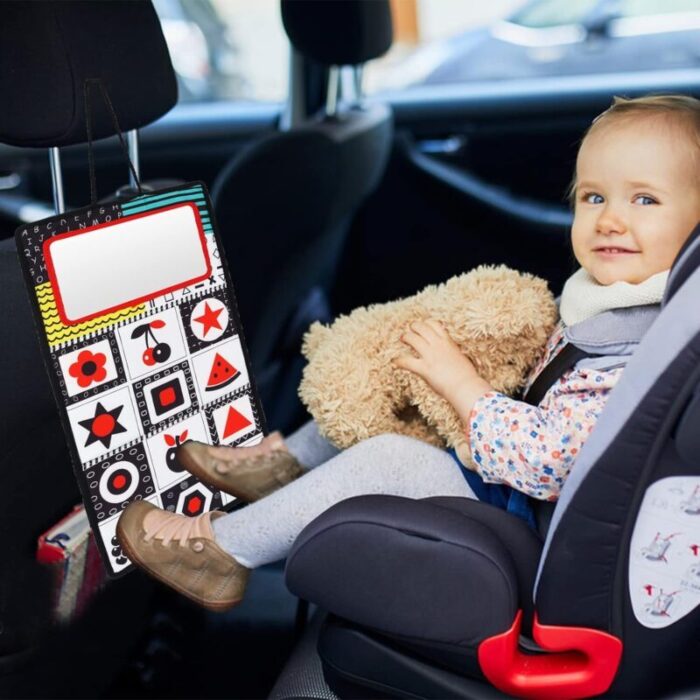 Un enfant dans un siège auto câline un animal en peluche à côté d'un organisateur coloré suspendu au siège avant, qui contient également un Miroir de ventre jeu Montessori.