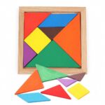 Le puzzle Montessori Petit Tangram Bois Couleurs comprend des pièces géométriques vibrantes comme des triangles et un carré dans un cadre en bois, avec quelques pièces dispersées à l'extérieur, idéal pour apprendre par le jeu.